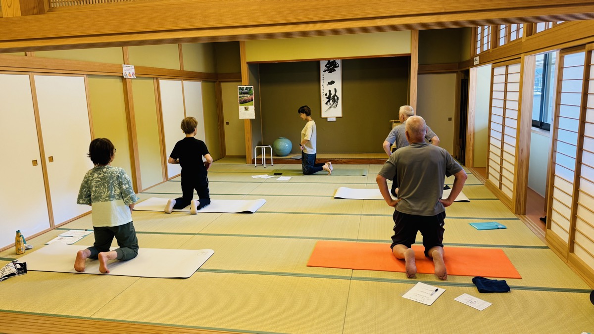 膝立ちの姿勢を練習する参加者と講師
